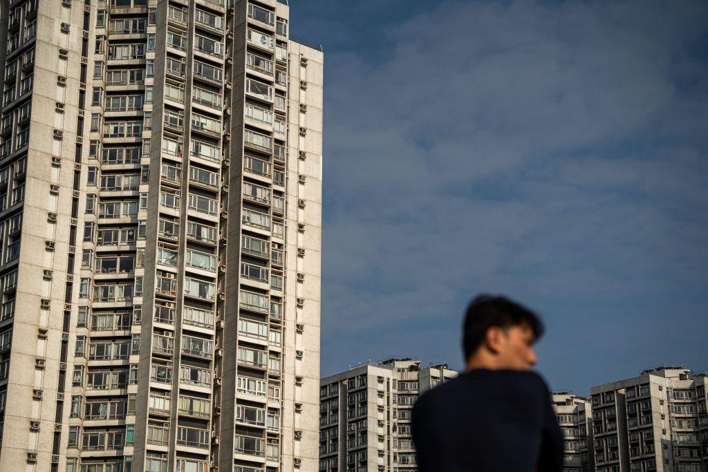 一名男子側著面，背景有住宅大廈。