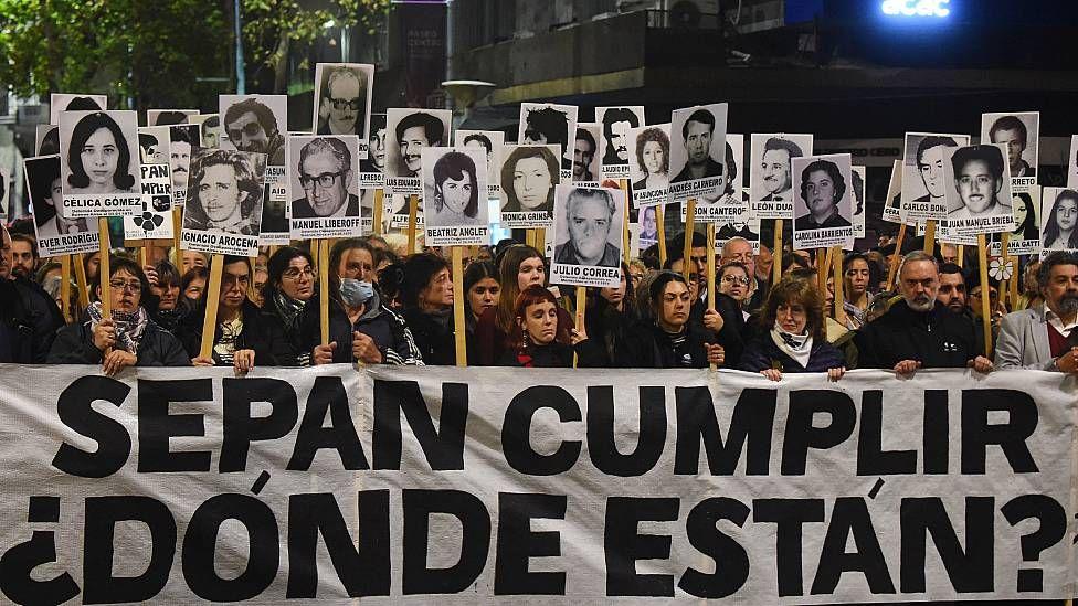 Cientos de personas marchan con carteles con imágenes de los desaparecidos en Uruguay. Al frente llevan una pancarta que dice "Sepan Cumplir. ¿Dónde están?"
