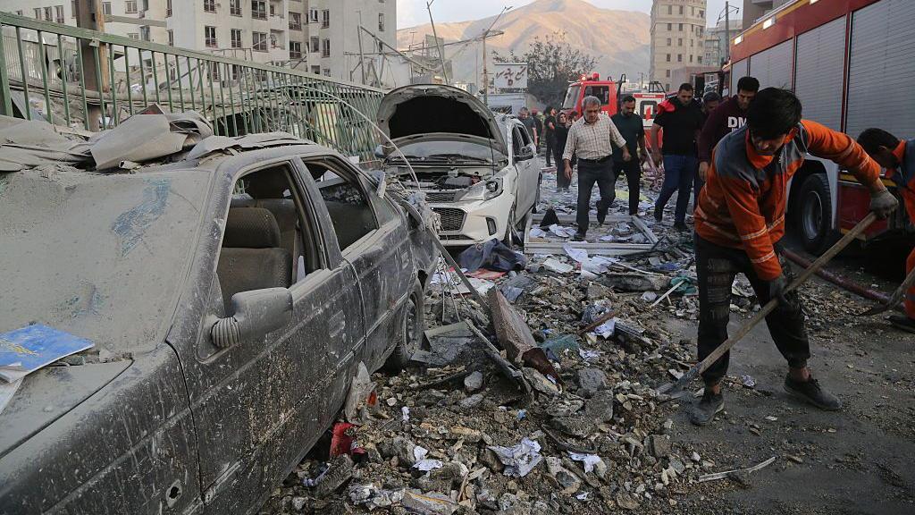 Ciudadanos iraníes recogen escombros en Teherán.