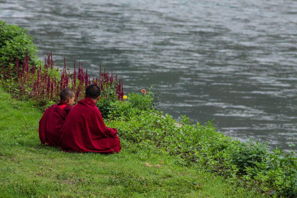 Dos jóvenes novicios budistas sentados a la orilla de un río. 