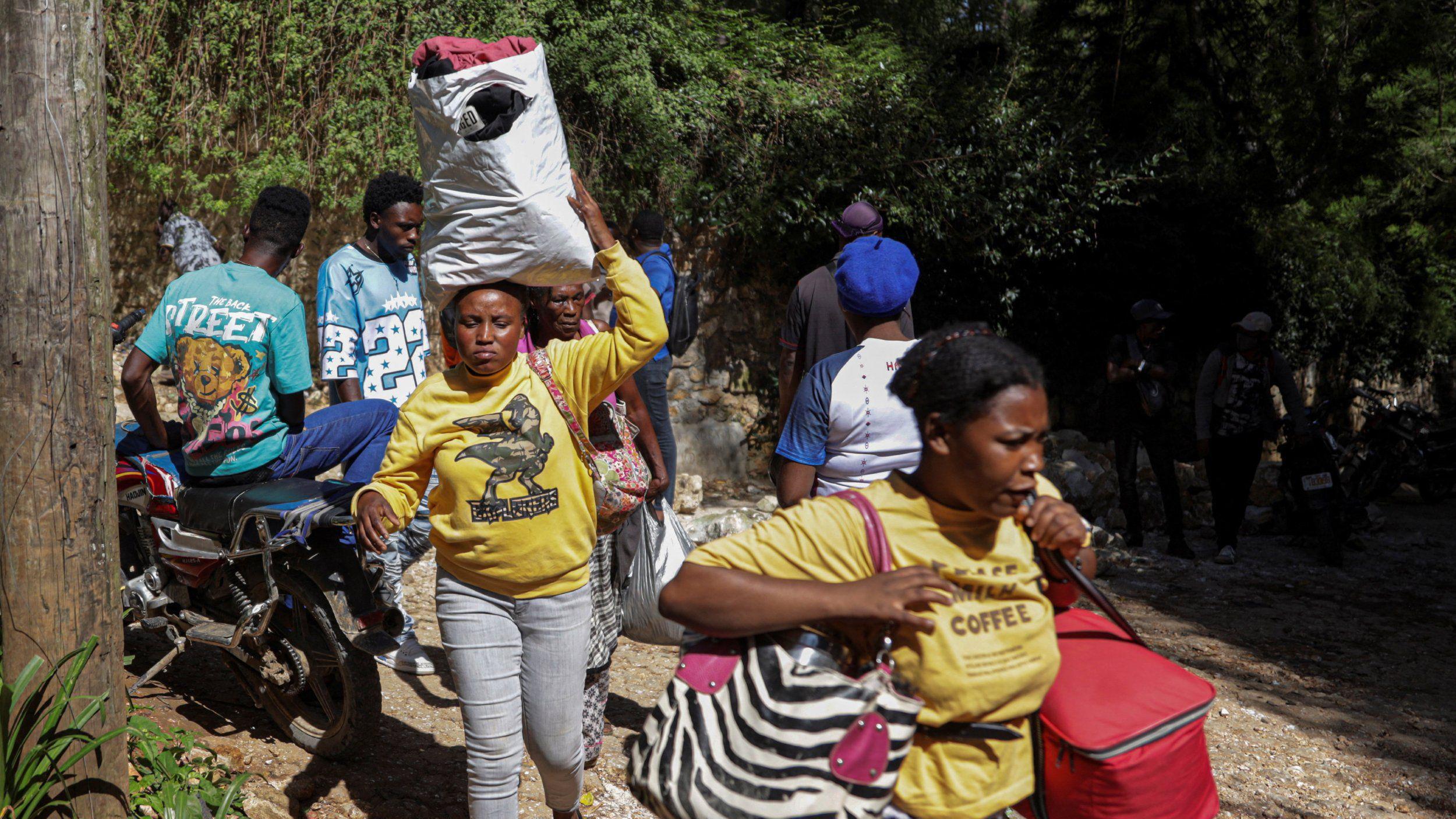 Las personas llevan consigo sus pertenencias mientras huyen de sus hogares tras una redada mortal llevada a cabo durante la noche por una banda armada, en las afueras de Puerto Príncipe.