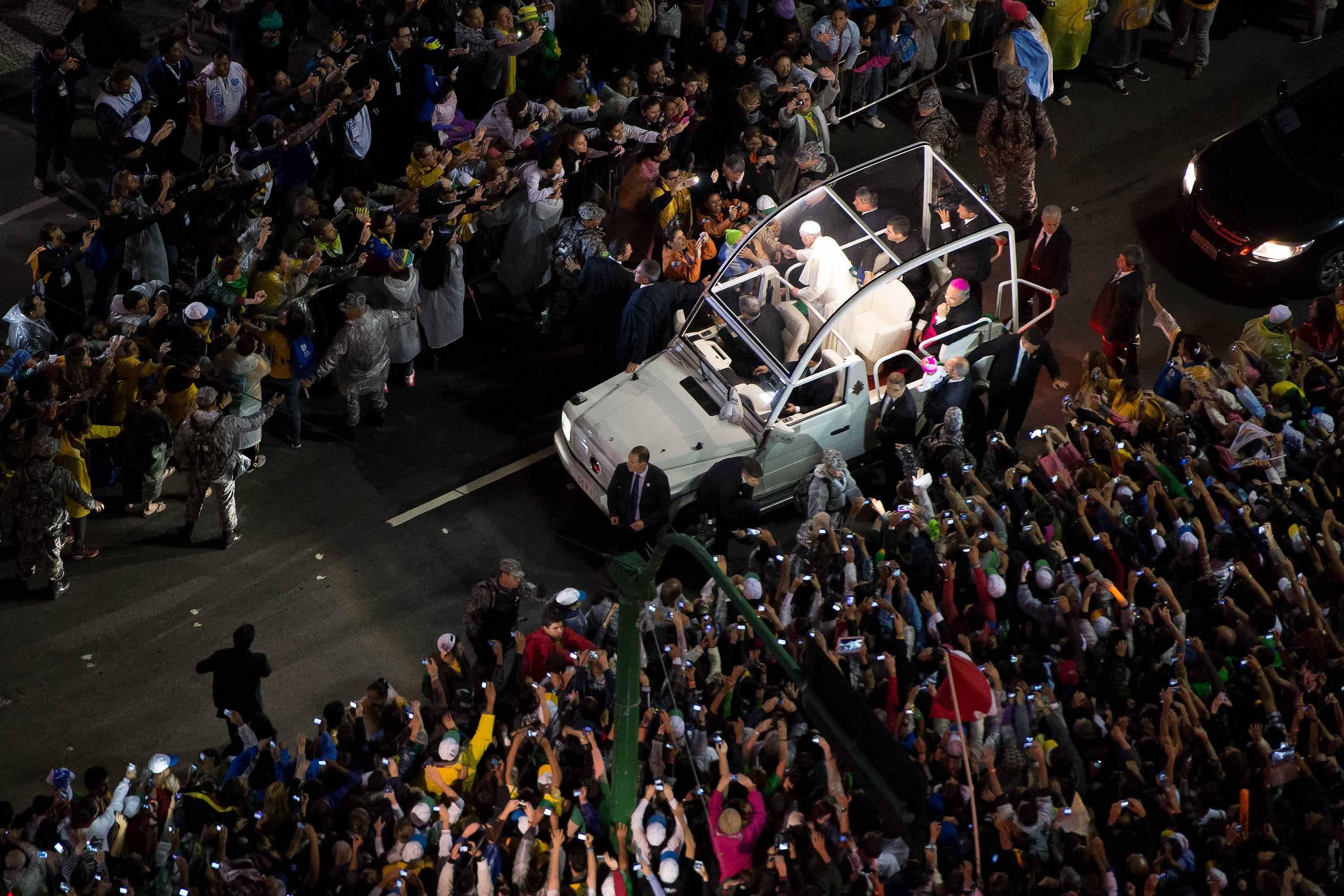 Papa Francisco no papamóvel cercado por fiéis na rua