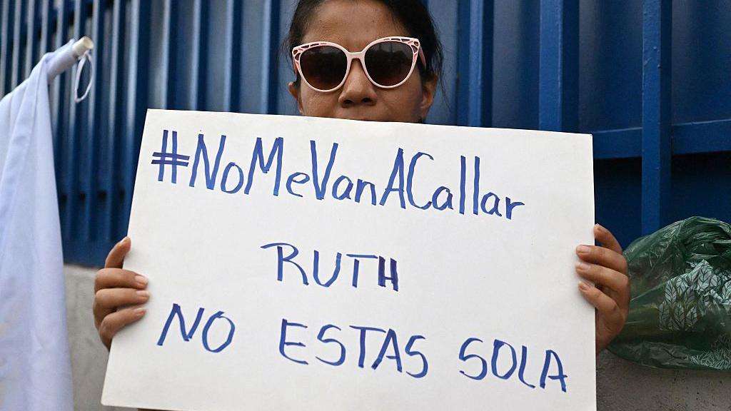Una partidaria de la abogada de derechos humanos y jefa del departamento de anticorrupción de la ONG Cristosal, Ruth López, sostiene un cartel afuera del Centro Judicial Isidro Menéndez en San Salvador, el 4 de junio de 2025. (Foto de Marvin RECINOS / AFP) (Foto de MARVIN RECINOS/AFP a través de Getty Images)
