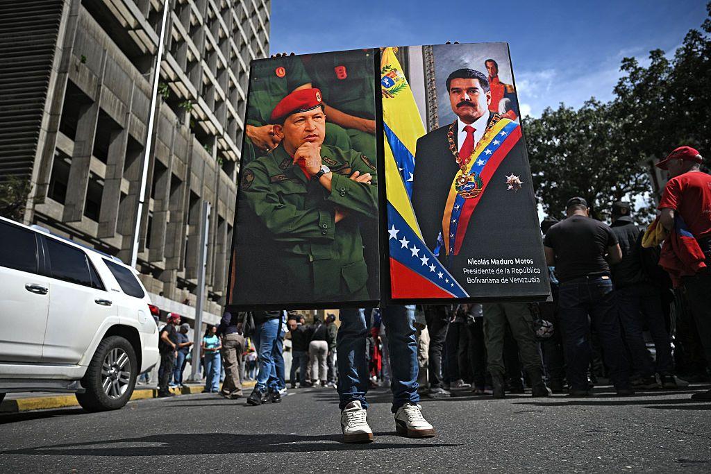 Un chavista sostiene un retrato de Chávez y otro de Maduro