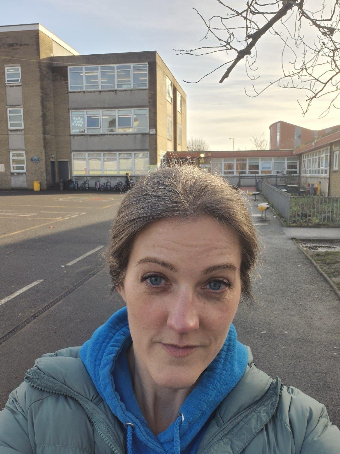 Ejmi Dikson u zelenoj zimskoj jakni i plavom duksu u dvorištu jedne od škola gde drži radionice