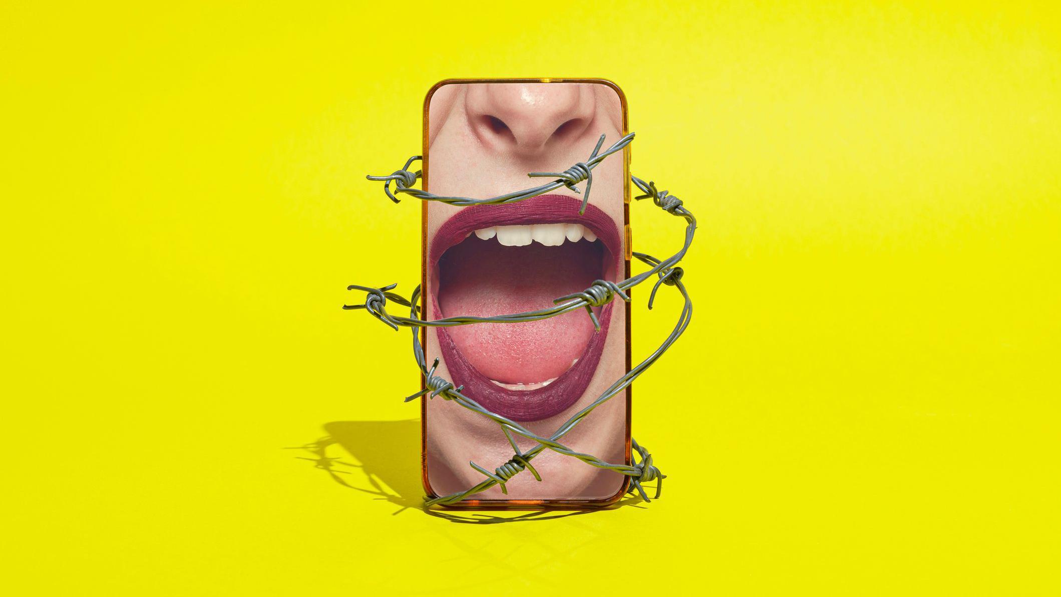 Teléfono inteligente con una boca de mujer gritando envuelta en alambre de púas sobre un fondo amarillo.