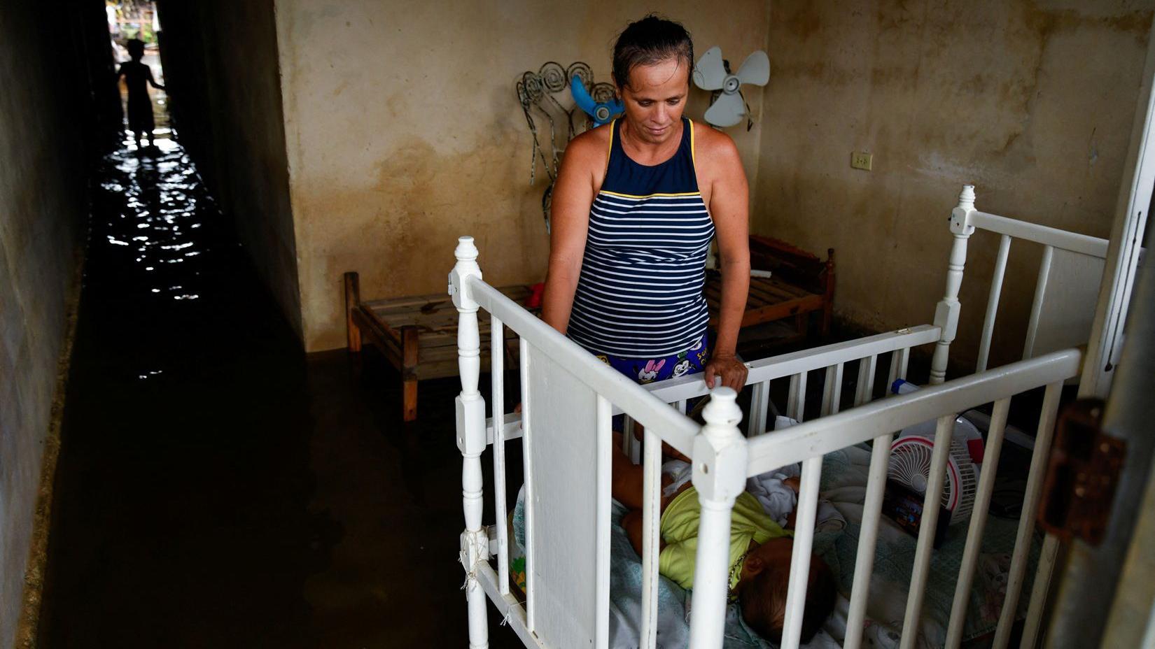 Mulher olha para o ber&ccedil;o de um beb&ecirc;