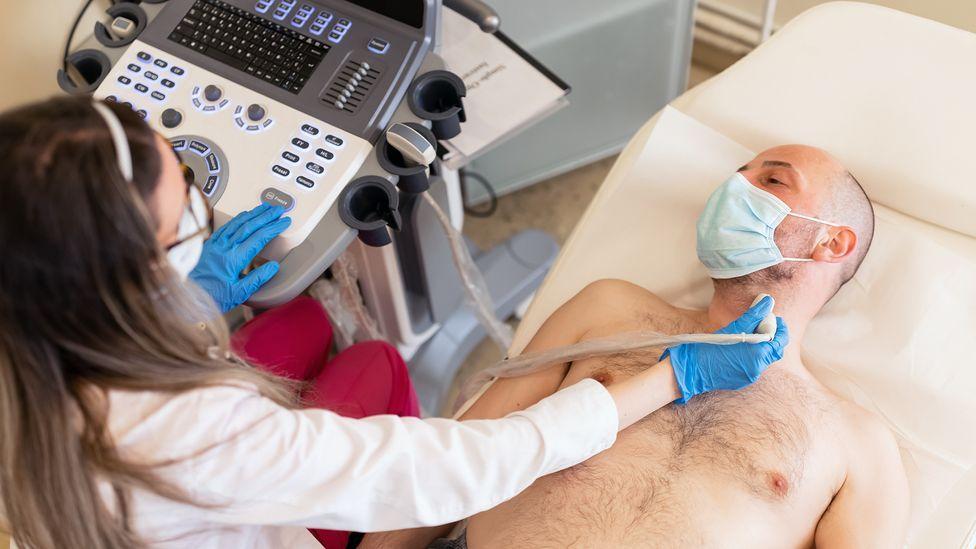 Homem deitado passa por exame de ultrassom da tireoide