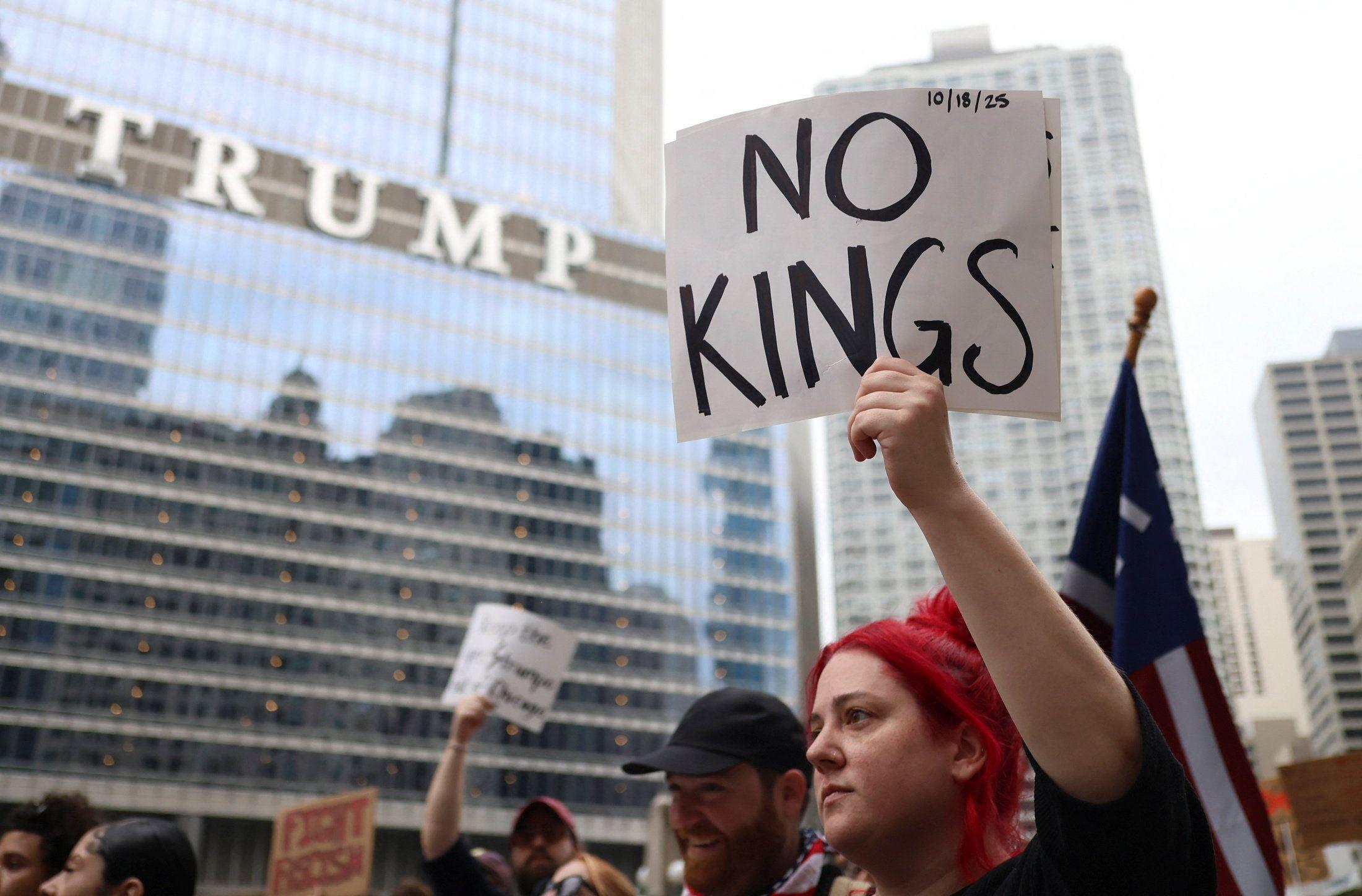 Una mujer de pelo rojo sostiene un letrero diciendo "no a los reyes" frente a la Torre Trump de Nueva York