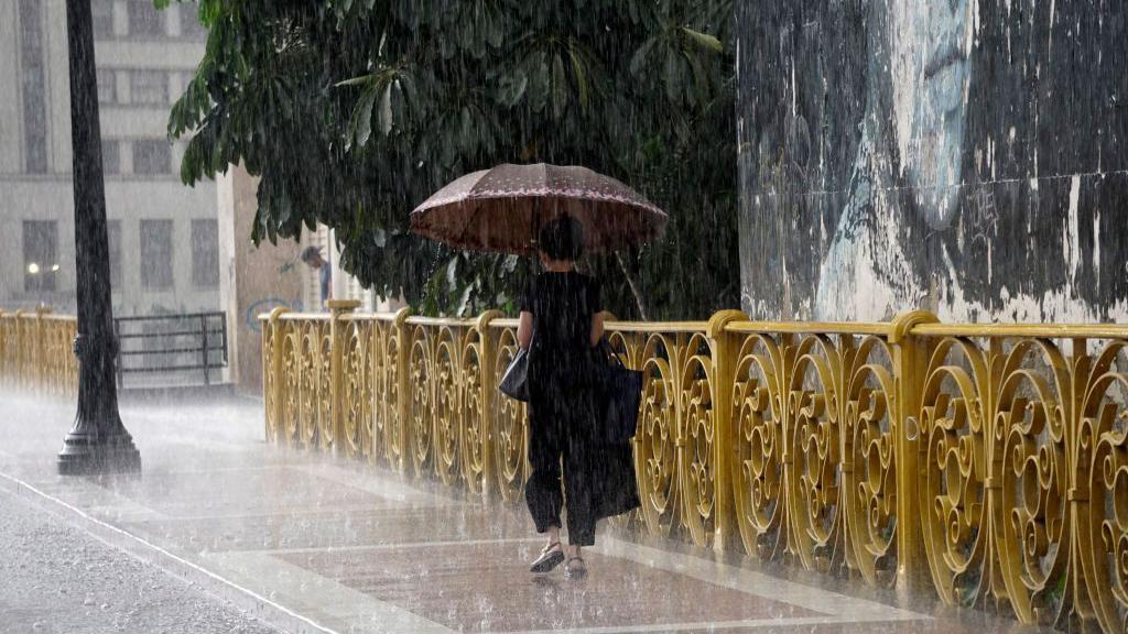 Pessoa usando guarda-chuva durante tempestade
