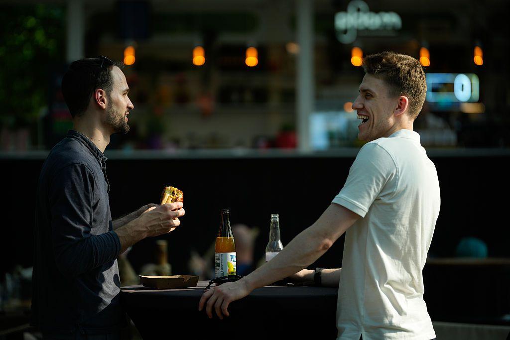 Dos hombres comiendo y charlando