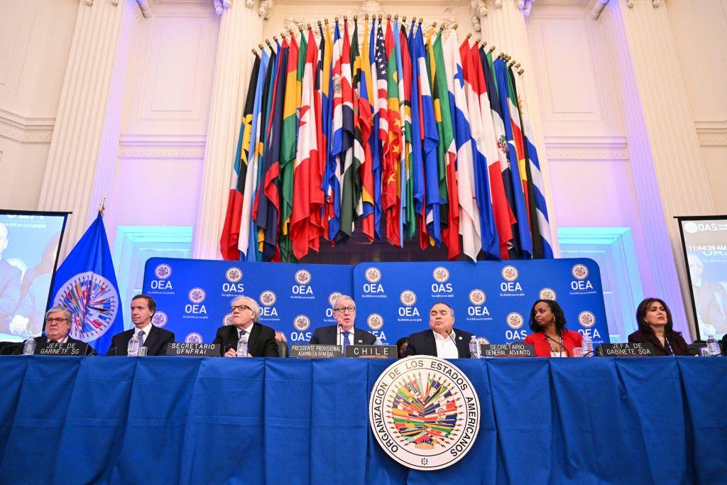 Vista de una reunión de la OEA, en la que se ven las banderas de sus miembros y el símbolo del organismo.