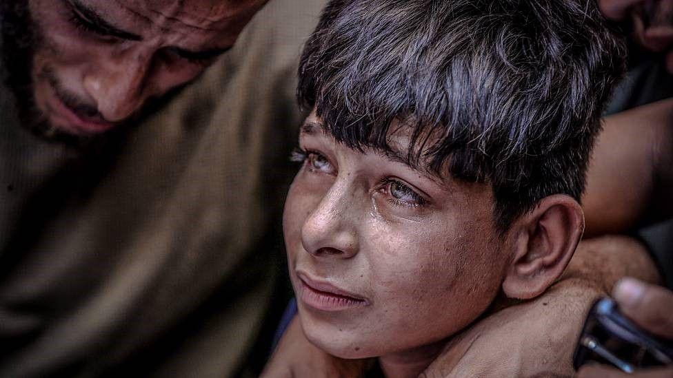 Un niño con lágrimas en los ojos junto a un hombre que llora