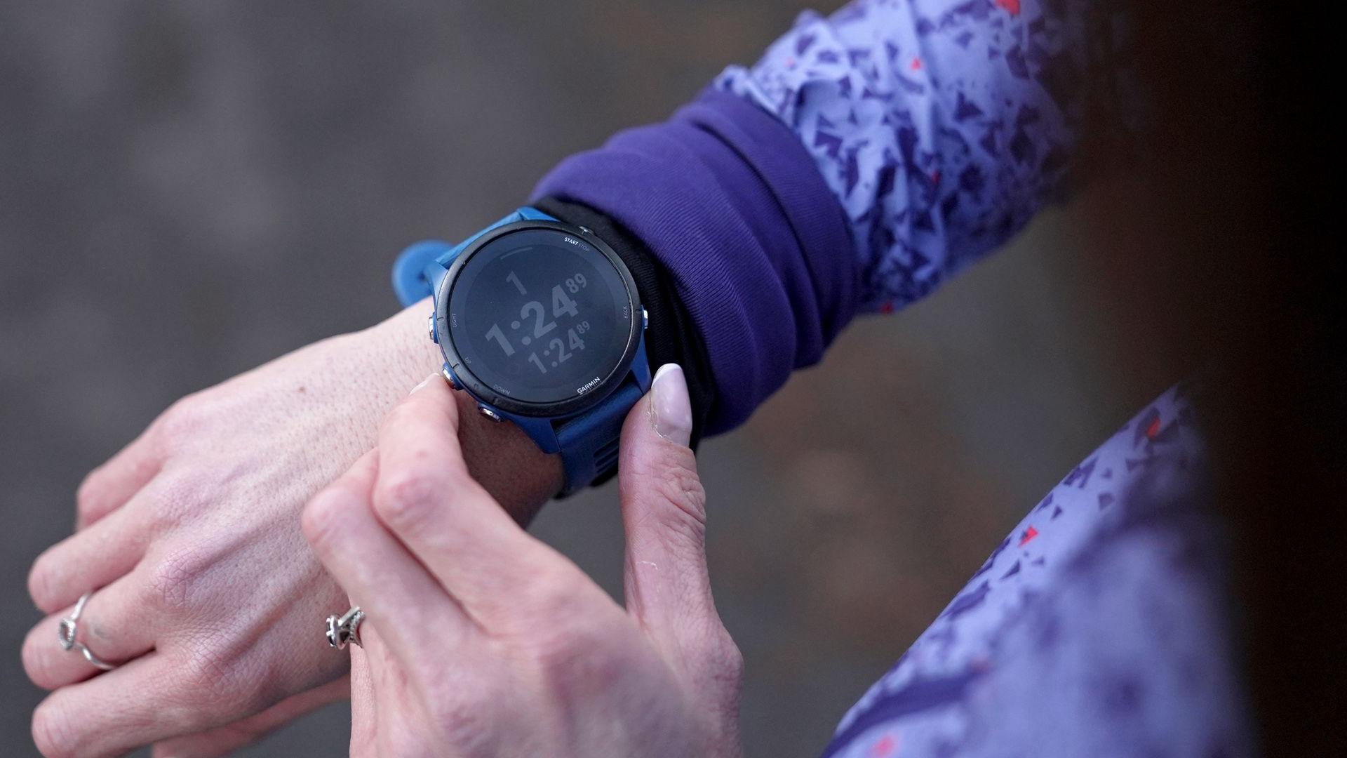 一名女性正在檢查她的智能手錶，按下按鈕並查看螢幕上顯示的統計數據