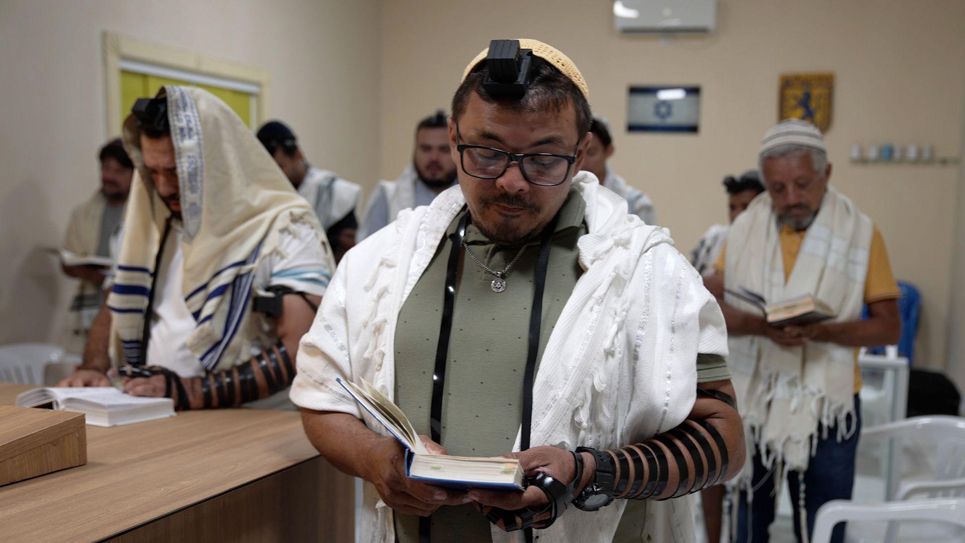 Homens com trajes ritualísticos judaicos durante oração em sinagoga