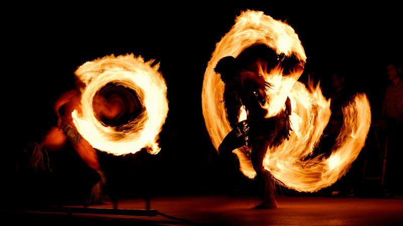 Dois dançarinos fazem apresentação com fogo em palco escuro