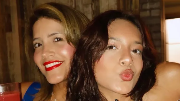 Dos mujeres mirando a la cámara. La mayor sonríe y la menor lanza un beso a la cámara. Son madre e hija.