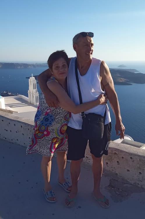 Andrea y Alejo posan con lo que parece ser el mar y pequeñas islas en el fondo. Ella lleva un vestido y lo abraza por la cintura, mientras él, con una camiseta sin mangas, le cruza un brazo por la espalda.