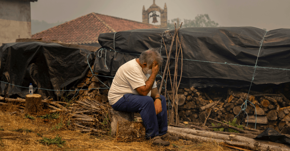 Un hombre sentado se sujeta la cabeza en una de las zonas afectadas por los incendios. 