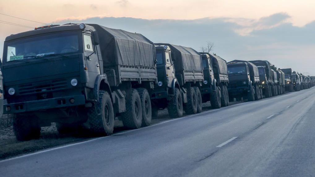 Una fila de camiones militares rusos circulando por una carretera.