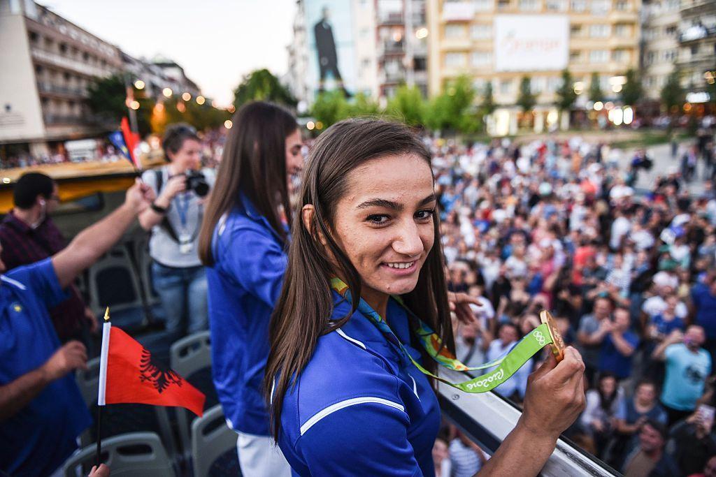 Majlinda sorrindo em cima de carro elétrico, rodeada por público embaixo 