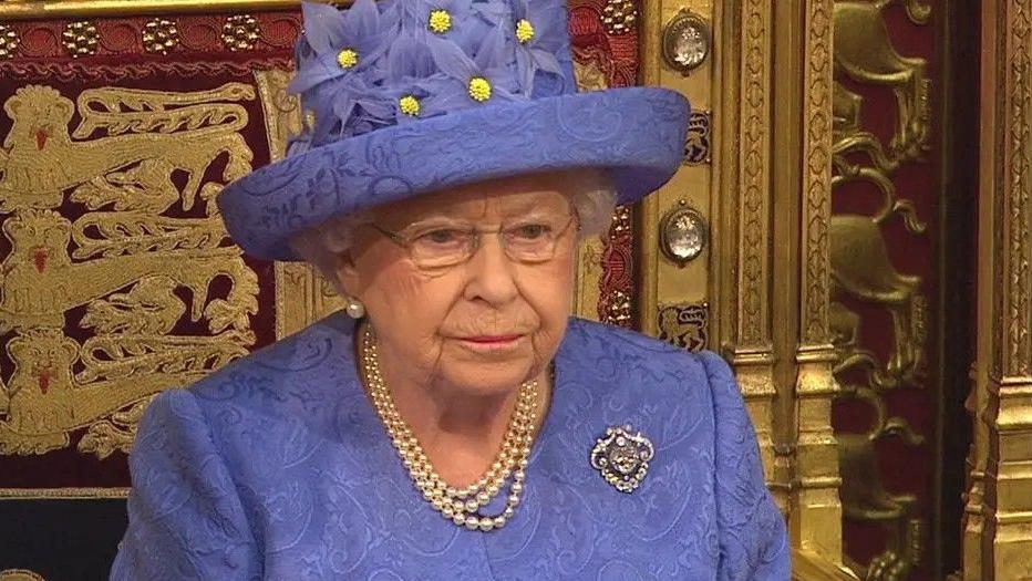 Rainha Elizabeth usando uma roupa e chapéu azul e colar de pérolas