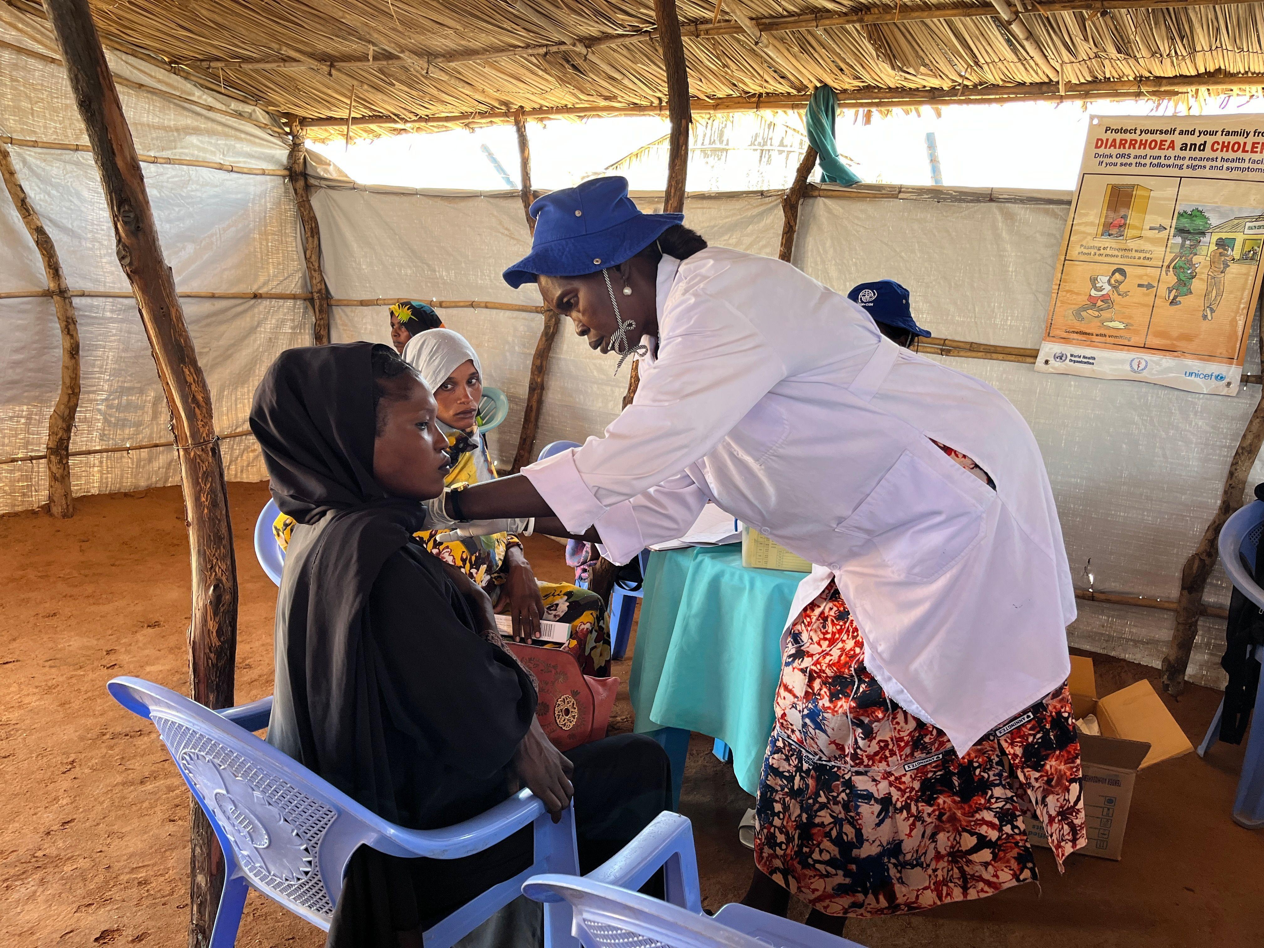 قصة أم سودانية عالقة هي وأطفالها بين صراعين 4 طبيب يرتدي معطفًا أبيض يعالج مريضًا يرتدي ملابس سوداء