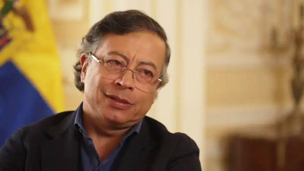 Gustavo Petro en entrevista con la bbc. Mira hacia la corresponsal wells. Lleva anteojos, una camisa azul y un saco negro. 