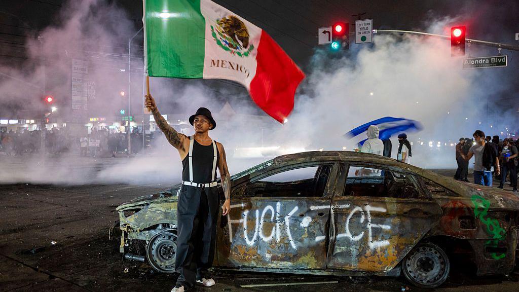 Un manifestante ondea la bandera de México en el barrio Compton de Los Ángeles.
