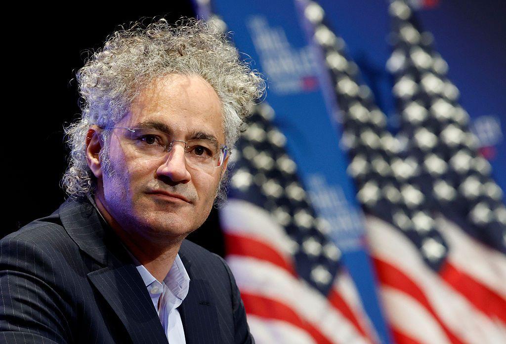 Alex Karp, con unas banderas estadounidenses desenfocadas en el fondo.