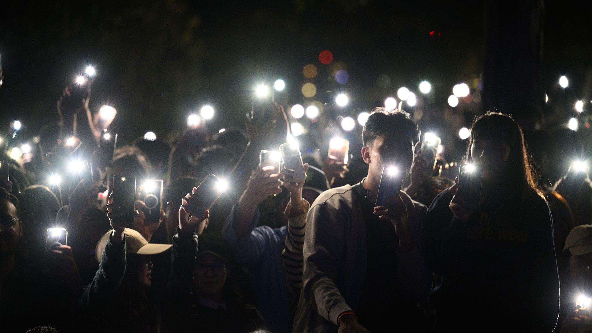 Un grupo de espectadores ilumina con las linternas de sus teléfonos móviles durante un homenaje a las víctimas del ataque terrorista de Bondi, durante las celebraciones de Nochevieja en Mrs Macquaries Point, en Sídney, Australia.