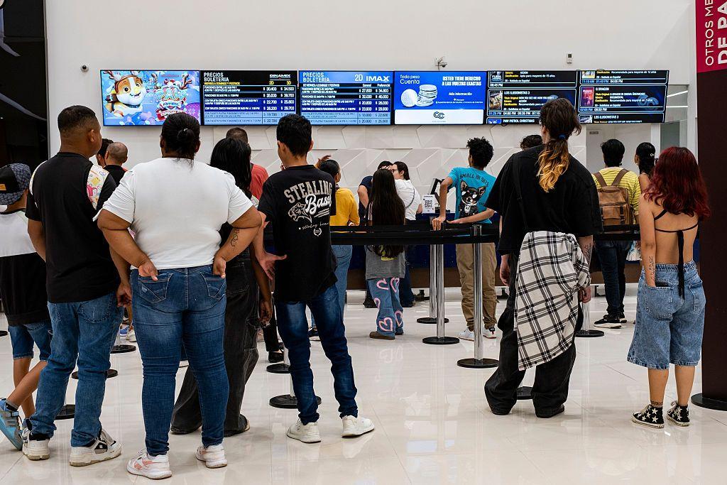 Un grupo de personas, vistas de espaldas, hacen fila en un centro de ocio de Bogotá. 