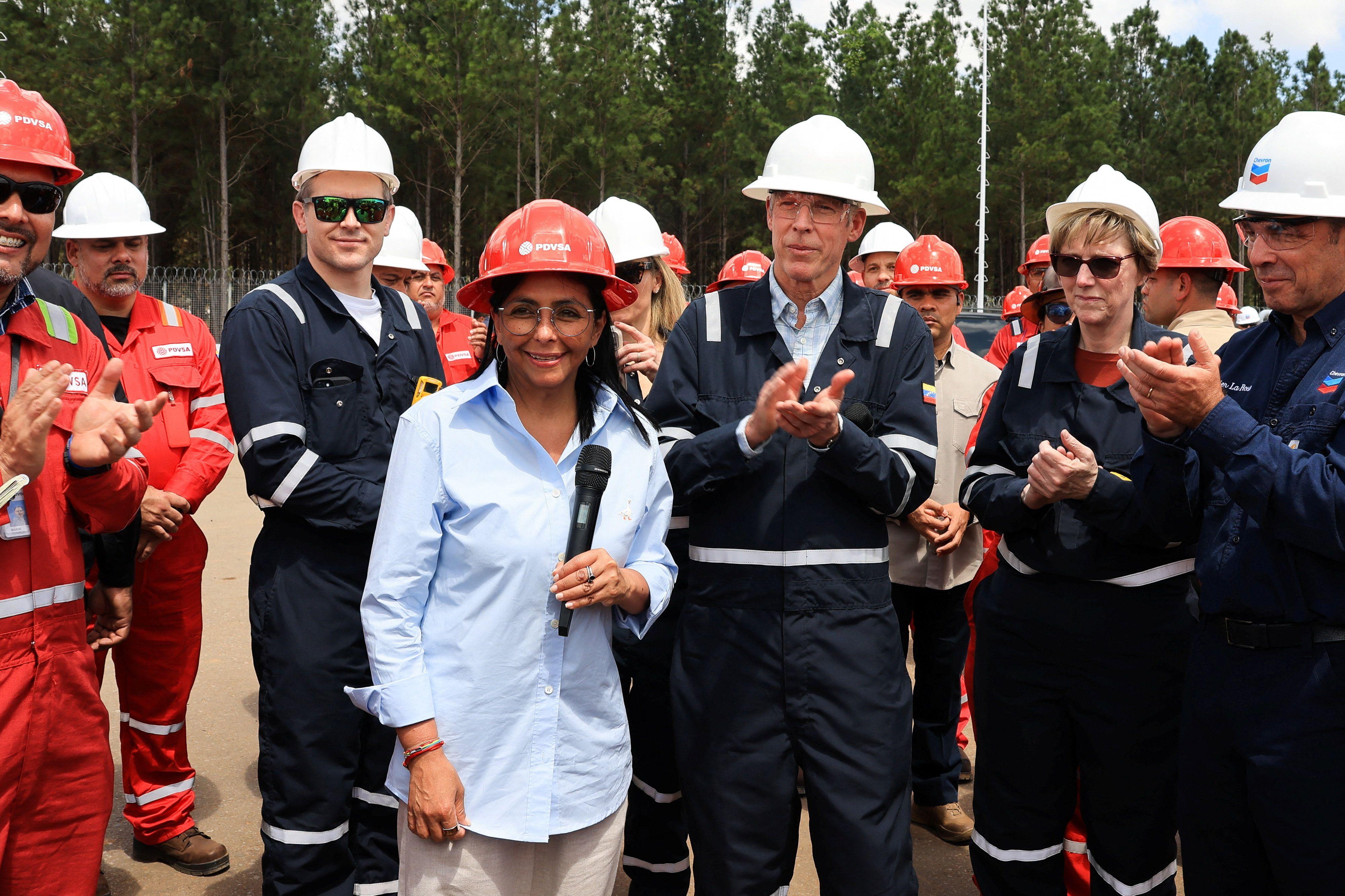 A presidente interina da Venezuela, Delcy Rodr&iacute;guez, e o secret&aacute;rio da Energia dos Estados Unidos, Chris Wright, visitam instala&ccedil;&otilde;es petrol&iacute;feras. Rodr&iacute;guez usa capacete laranja e camisa azul clara e Wright usa um capacete branco e macac&atilde;o azul