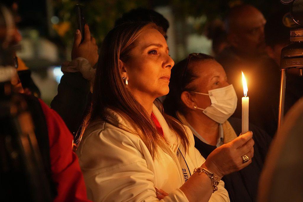 Una mujer con una vela encendida entre un grupo de personas