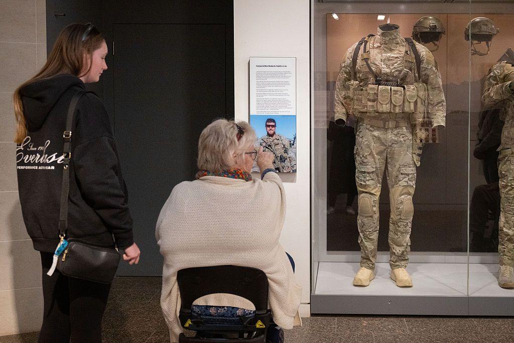 Una señora en silla de ruedas junto a otra más joven ven uno de los uniformes de Roberts-Smith en el Museo de la Guerra de Australia.