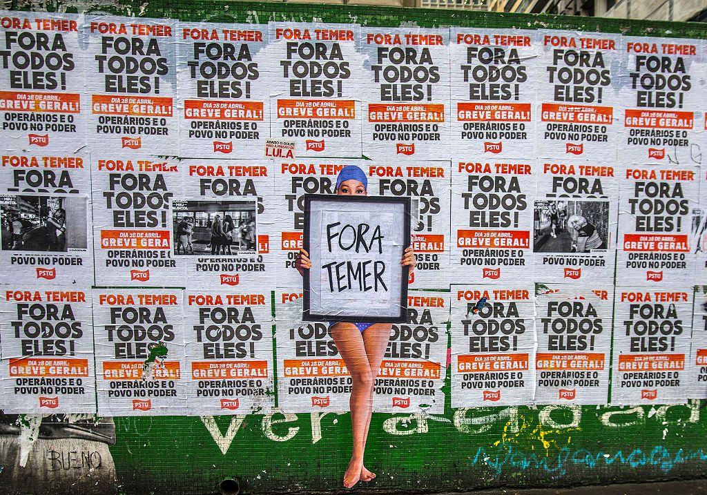 Una obra de arte urbano realizada con la técnica de engrudo (wheat-paste) por el artista Luis Bueno, que representa a un bañista sosteniendo un cartel con la frase «Fuera Temer», en la Avenida Paulista, el 19 de mayo de 2017 en São Paulo, Brasil.