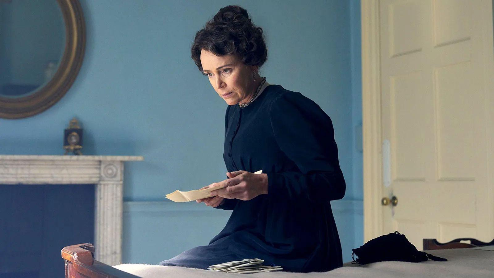 Keeley Hawes interpretando a Cassandra, sentada en una cama con las cartas de Jane Austen en la mano