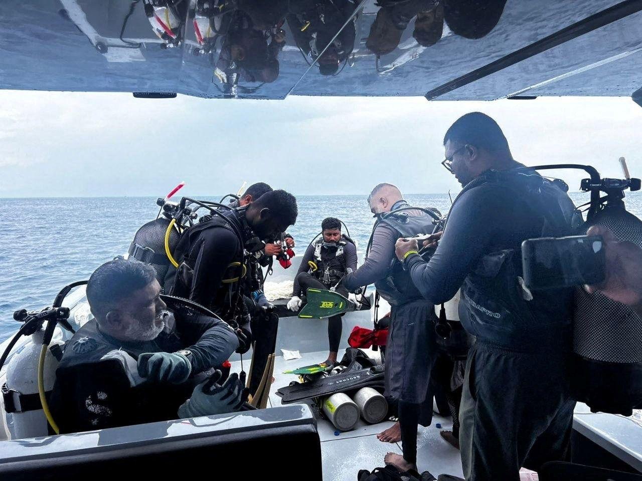 Un grupo de buzos se prepara para saltar al agua en un barco.