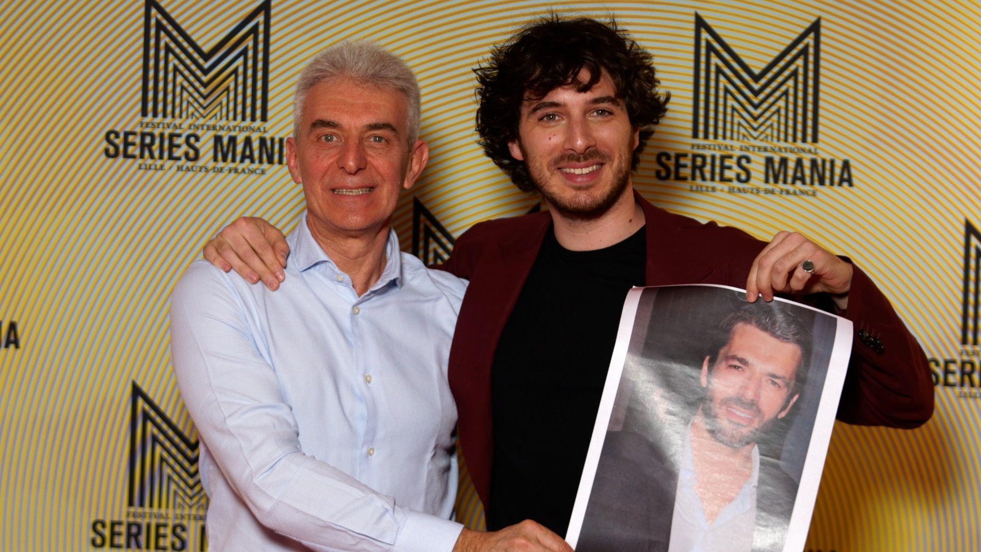 Actor Pierpaolo Spollon (right) holds up a poster showing his TV character based on Pierdante Piccioni (left), at the Series Mania Festival, on 21 March 2022 in Lille, France