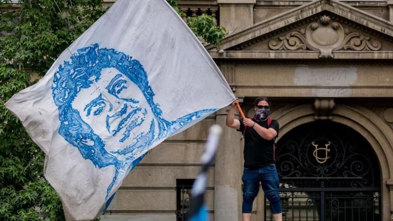 Homem agita uma bandeira com a imagem de V&iacute;ctor Jara