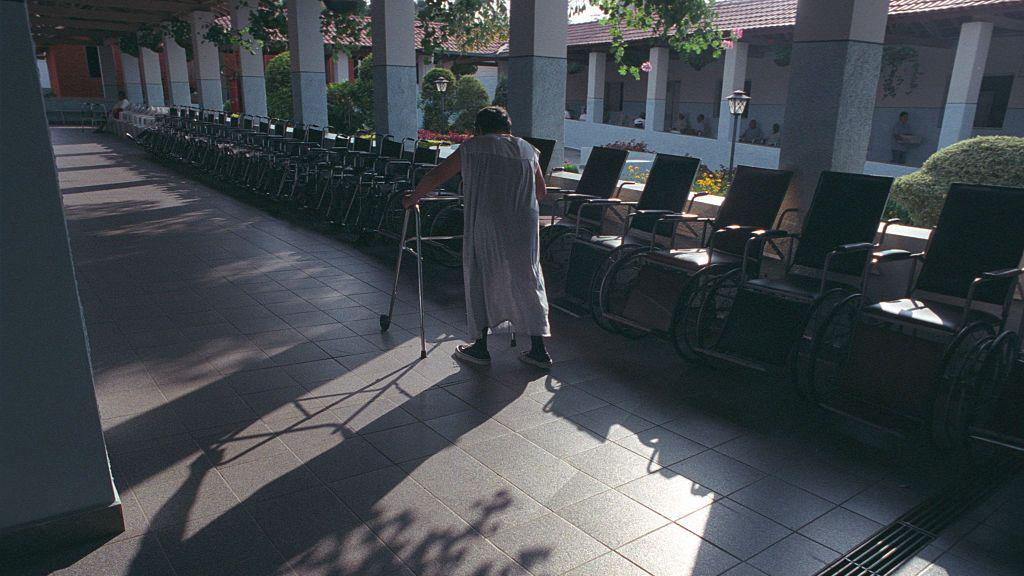 Foto de uma pessoa idosa caminhando com um andador. 