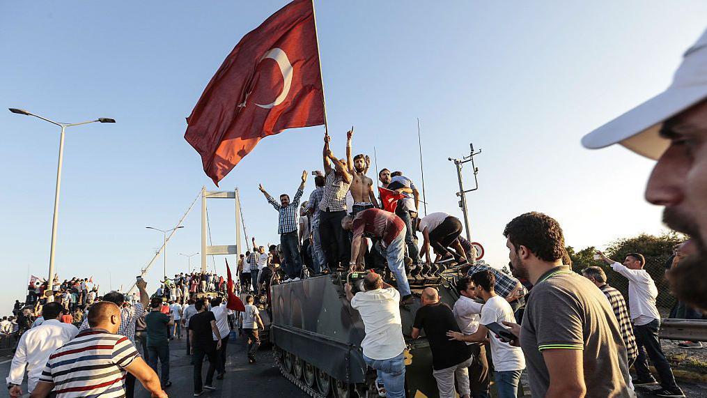 Supporters of President Recep Tayyip Erdogan wave Turkish flags as they capture an army tank after soldiers involved in the coup attempt have surrendered on Istanbul's Bosphorus Bridge