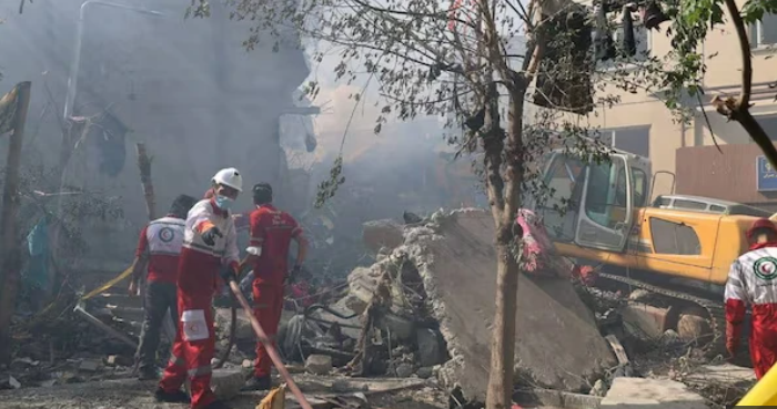 12 يوماً تهزّ الشرق الأوسط: تسلسل المواجهة الخاطفة بين إيران وإسرائيل 3 صورة تظهر أشجاراً مدمرة وركام مبانٍ، بينما يحاول رجال الهلال الأحمر الإيراني إزالة آثار الدمار.