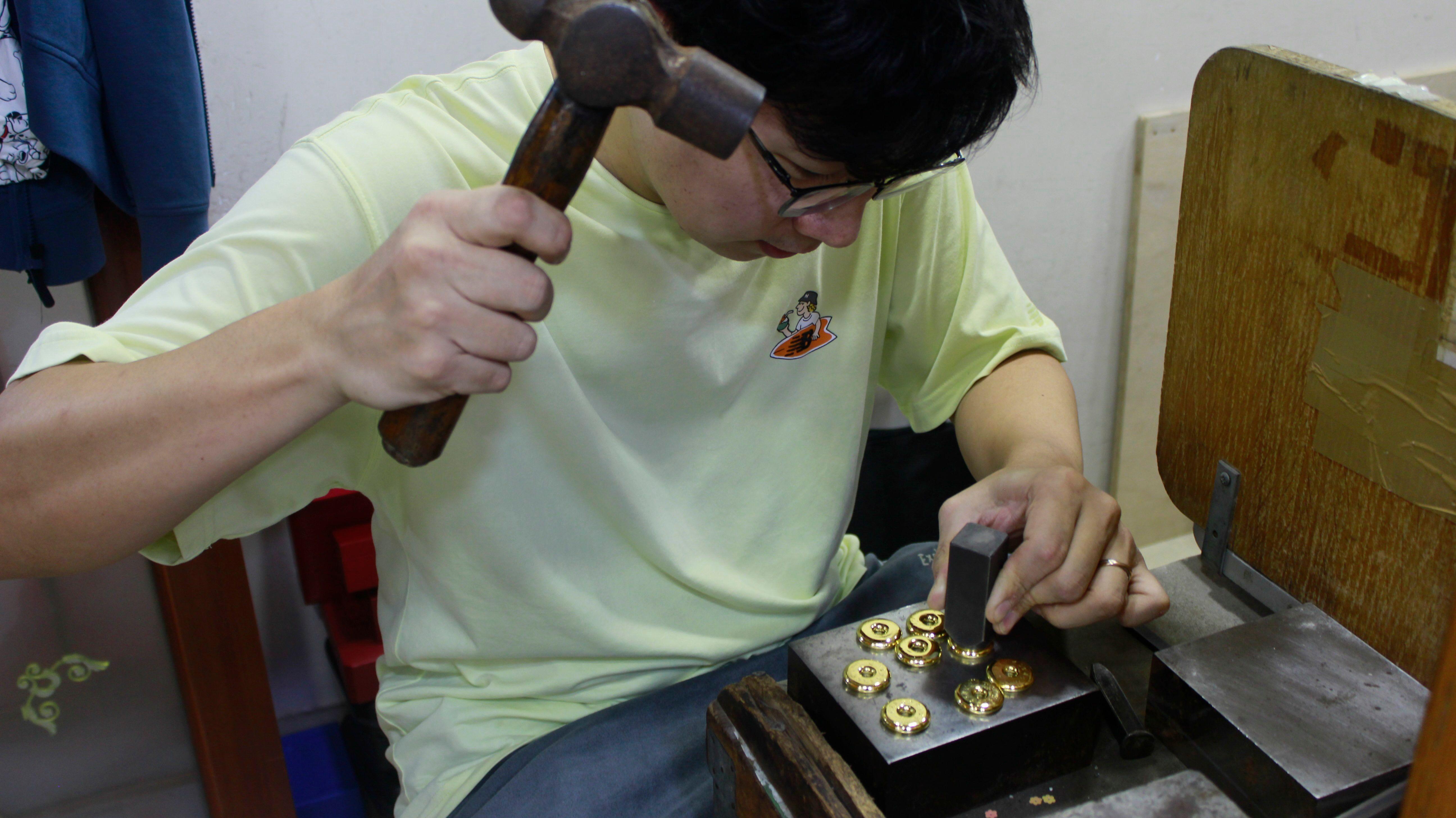 一名男子正在打製金粒。