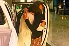 The moment Sammi and Safi were reunited on his return and embrace - they are standing next to an open door of a car, with Safi wearing white traditional Shalwar Kameez and Sammi wearing a printed Shalwar Kameez.