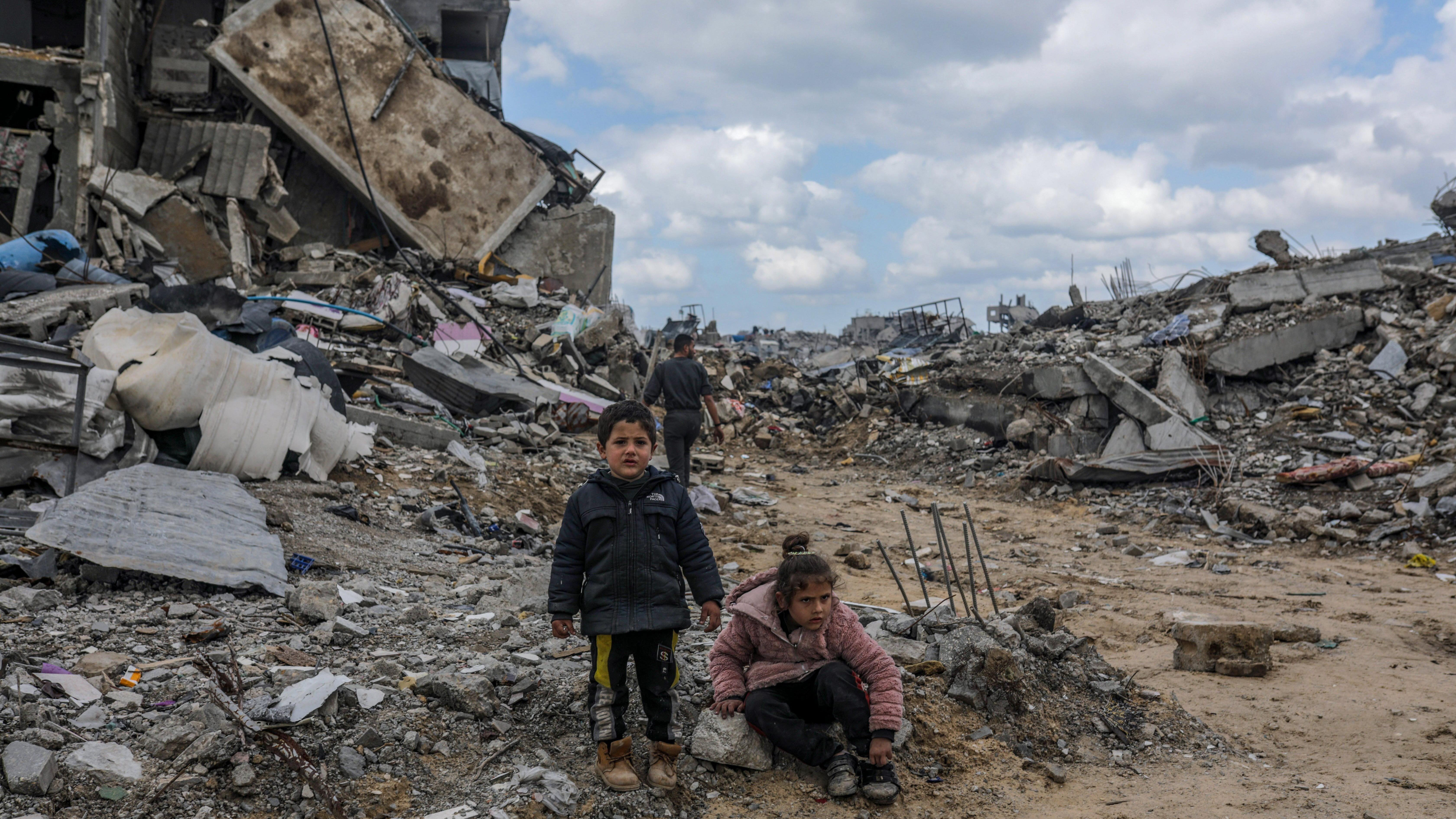 أطفال فلسطينيون يلعبون بالقرب من ملاجئ عائلاتهم التي أقيمت بين أنقاض المباني المدمرة وسط وقف إطلاق النار بين إسرائيل وحماس، في جباليا، شمال قطاع غزة في 13 فبراير/شباط 2025.