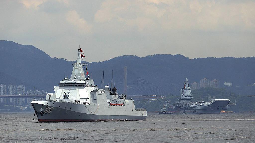 El segundo portaaviones de China, el Shandong, y el destructor de escolta Yanan están anclados después de llegar a Hong Kong, junto con un pequeño remolcador.