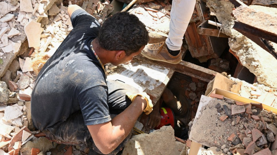 Hombre mira por un agujero mientras rescatistas buscan sobrevivientes.