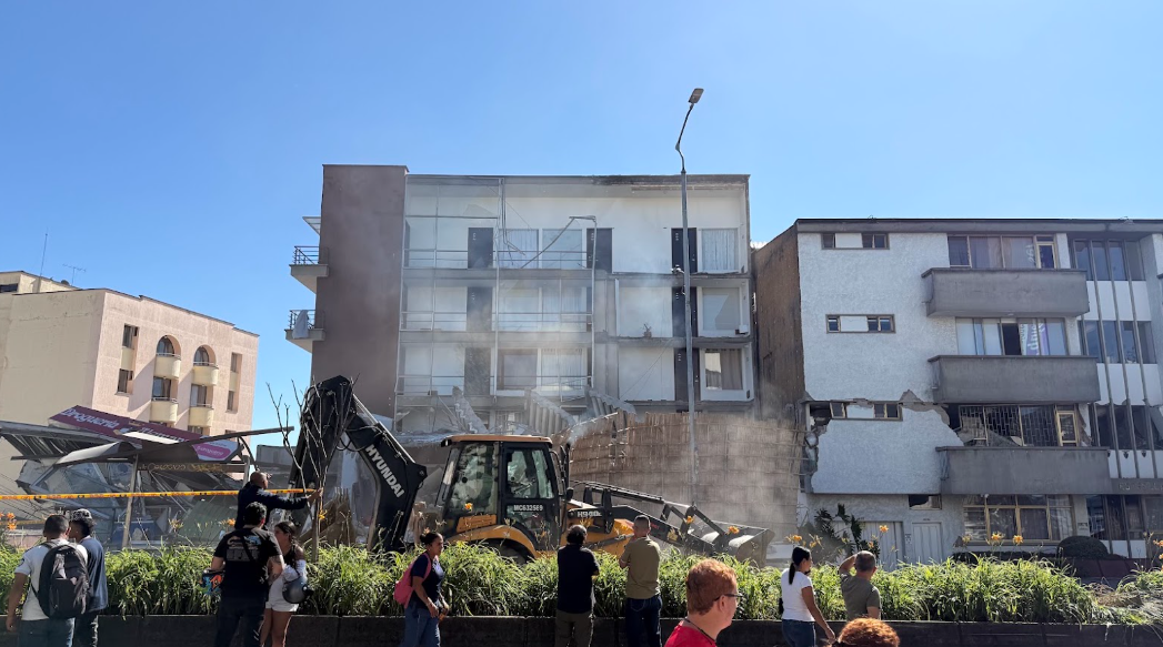 Vecinos de Manizales observan los daños en los edificios mientras una excavadora retira escombros tras el terremoto de este lunes 10 de agosto de 2026 en Colombia.