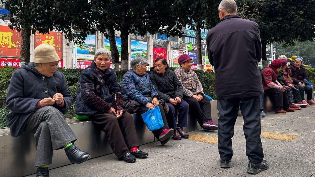 2025年3月，中國重慶，一群老人坐在城區的公共長椅上交談